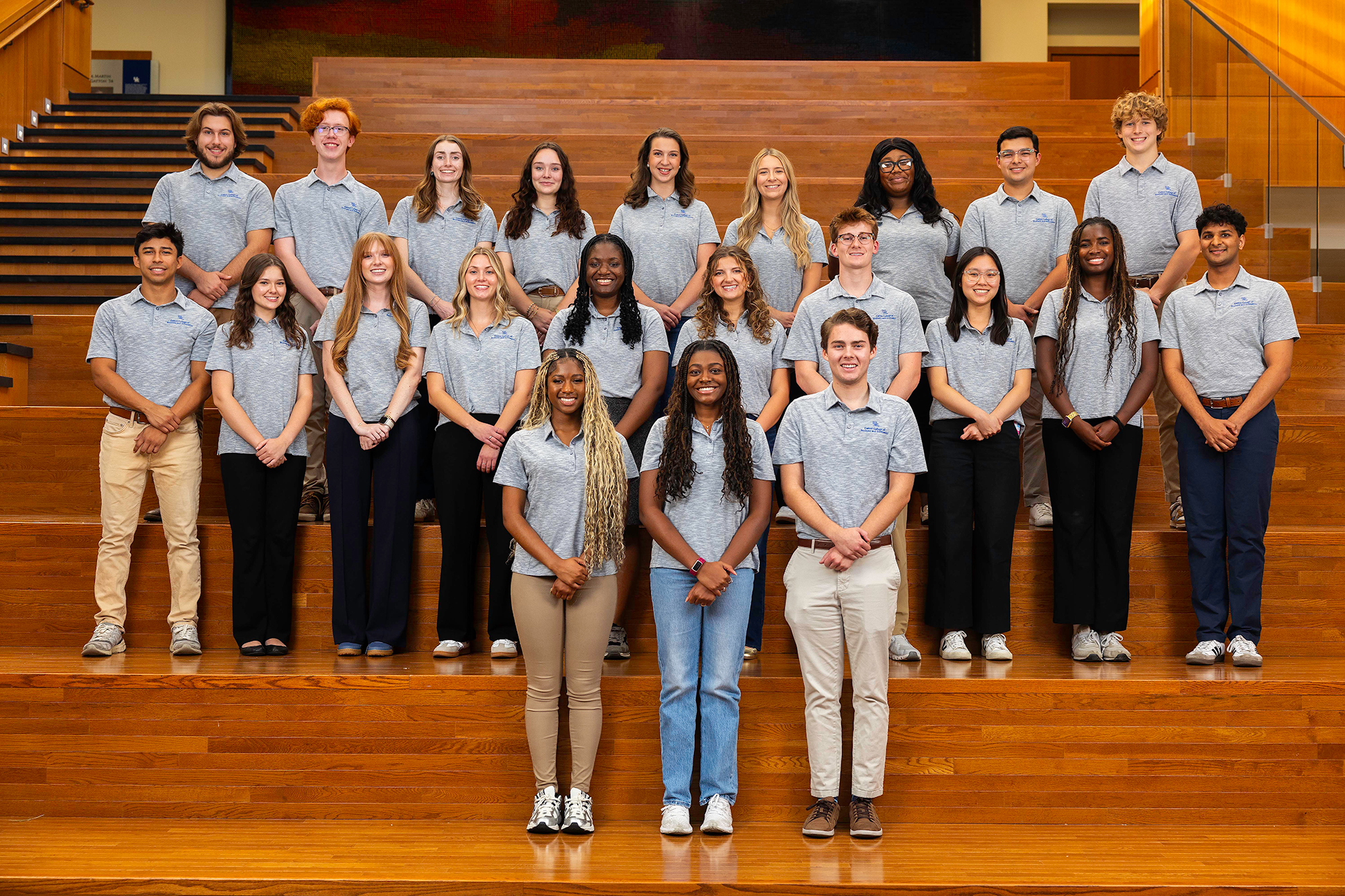Gatton Ambassadors, composed of 22 members, stand on the atrium steps in blue gray uniformed shirts