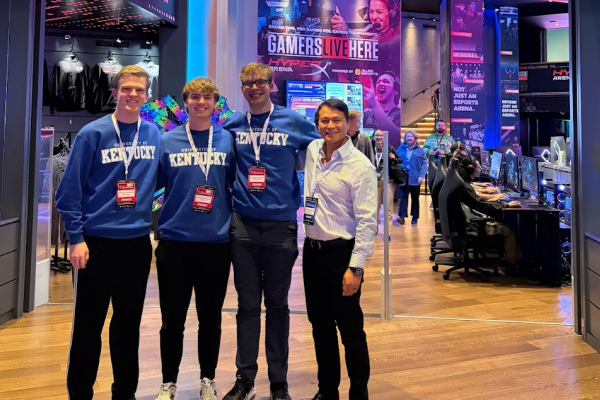 UK Excel Financial Modeling team poses for a picture. From left to right, Paul Kreinbrink, John Lubert, Colin Albrecht, John Saliling. All team members are wearing coordinating UK sweatshirts and Microsoft Excel Collegiate Challenge lanyards and name tags