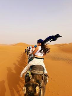Woman ridding a camel in a caravan across the desert