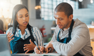 A man and women in aprons planning and speaking to each other