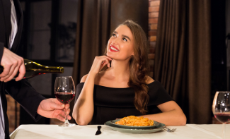 Women watching waiter pour wine into wine glass