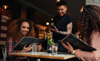 Two people ordering food and drinks with the help of their waiter