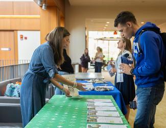 Organizer handing out information while a student reads more about the program.