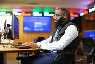 A professional student works at a computer desk in the Seale Finance Learning Center