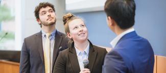 three professionally dressed future business leaders lookup towards the presentation screen to reflect on the topic of their presentation with their audience.