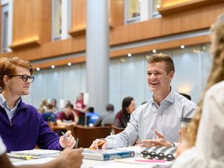 Three students discuss supply chain management strategies in Gatton B&E's atrium.