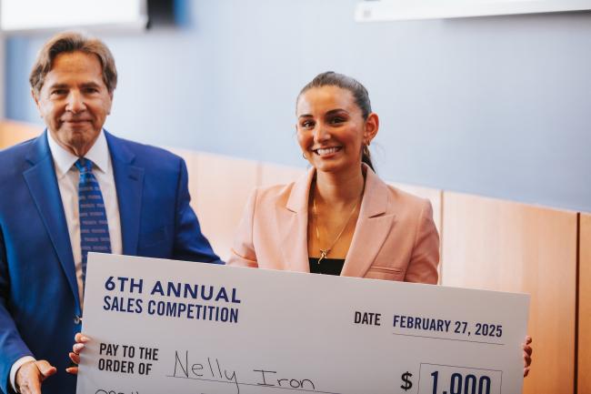 The winner of the 6th annual sales competition, Nelly Iron, poses with event coordinator, Michael Johnston, with her first prize check