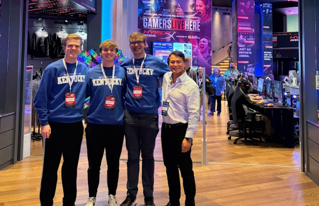 UK Excel Financial Modeling team poses for a picture. From left to right, Paul Kreinbrink, John Lubert, Colin Albrecht, John Saliling. All team members are wearing coordinating UK sweatshirts and Microsoft Excel Collegiate Challenge lanyards and name tags
