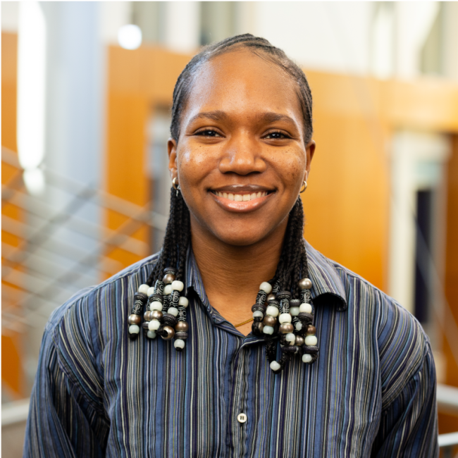Timika Scarlett's headshot. She is wearing a dark blue collared shirt and the Gatton College of Business is in the background