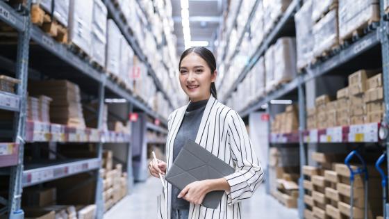 Woman standing in warehouse with clipboard
