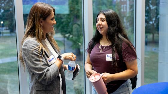 A student speaking with an employer in front of a ground floor window.