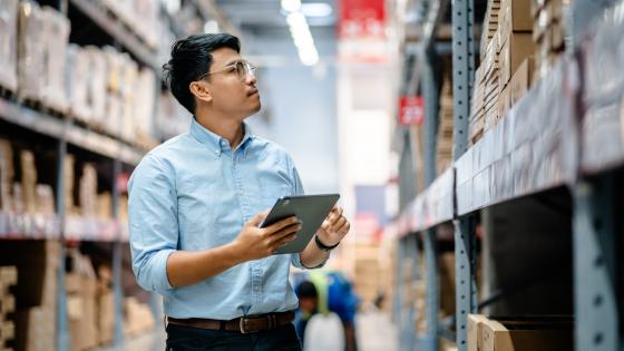 Businessmen or manager use a digital tablet to check the stock inventory on shelves in large warehouses, a Smart warehouse management system, supply chain and logistic network technology concept