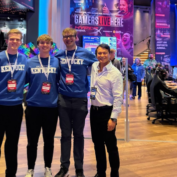 UK Excel Financial Modeling team poses for a picture. From left to right, Paul Kreinbrink, John Lubert, Colin Albrecht, John Saliling. All team members are wearing coordinating UK sweatshirts and Microsoft Excel Collegiate Challenge lanyards and name tags